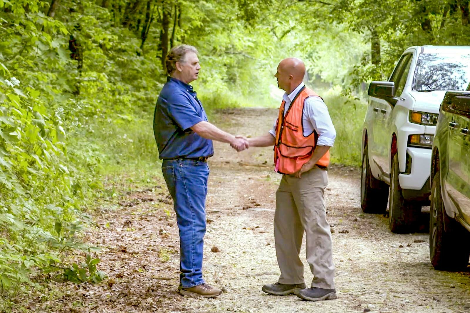 two men shaking hands in a forest