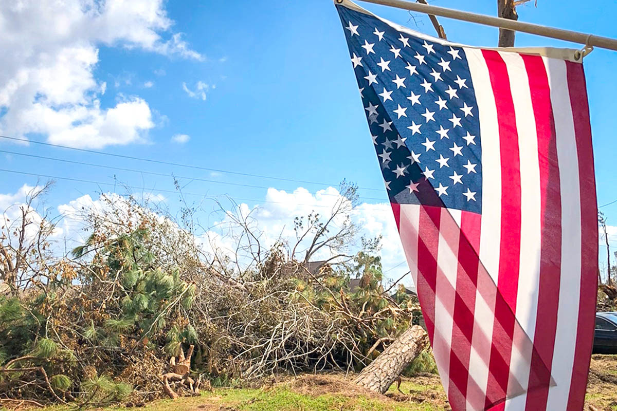 photo of hurricane damage with an American flag in the foreground