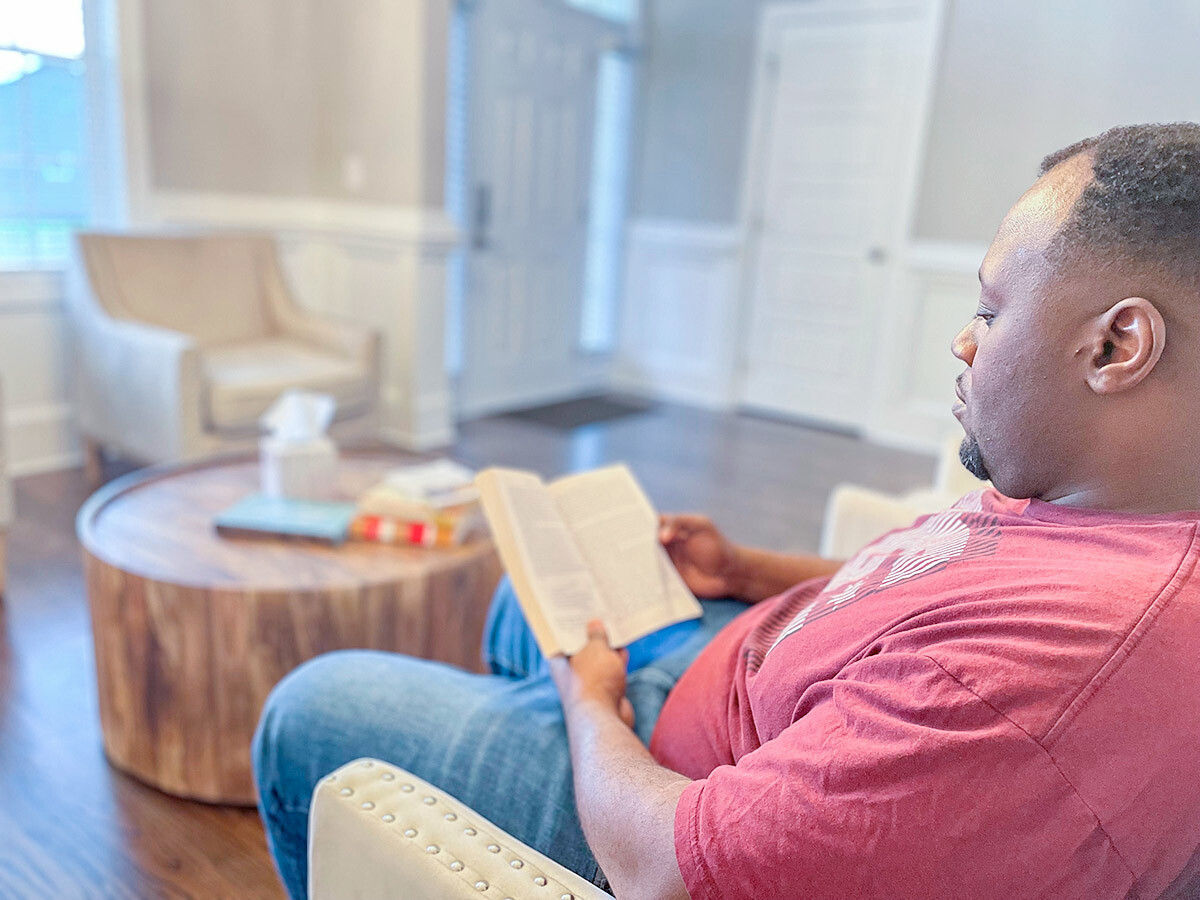 Photo of Demetrius Wood reading in his living room