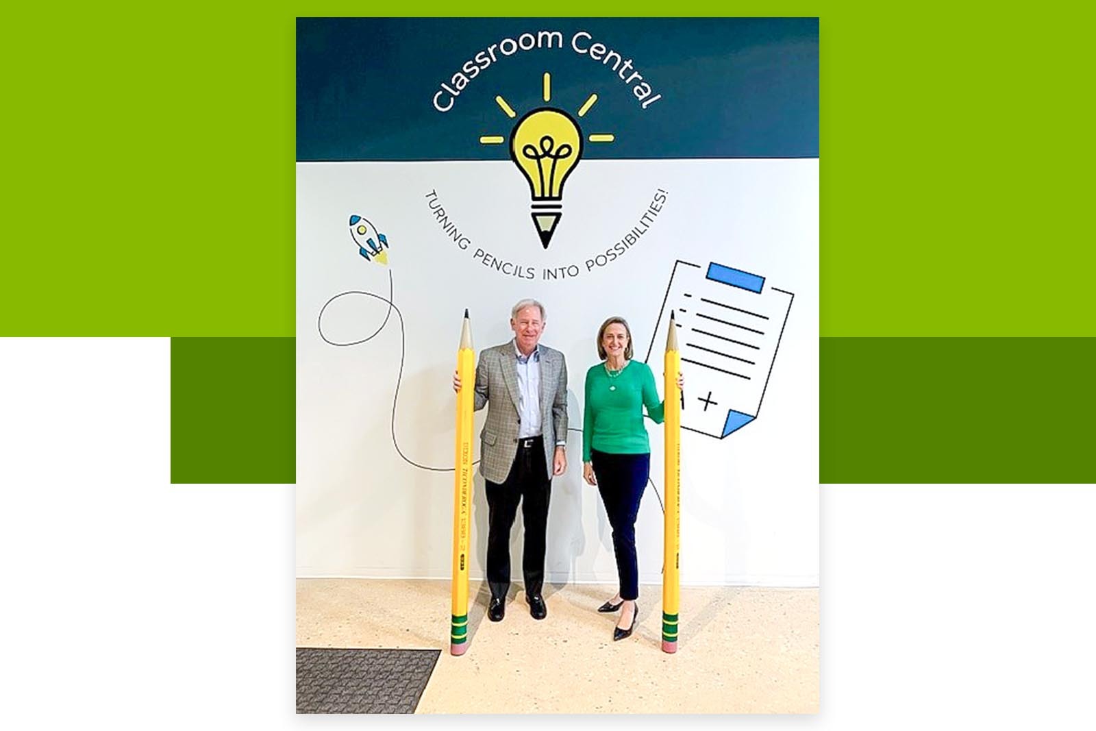 Two teachers standing next to the wall with Classroom Central...