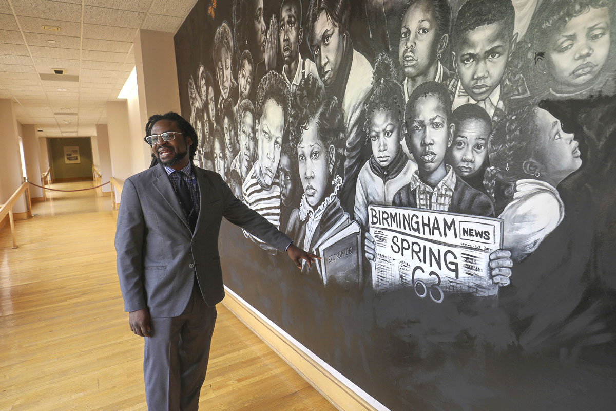 Charles Woods III shows off Ronald McDowell’s evocative mural at the Birmingham Civil Rights Institute.