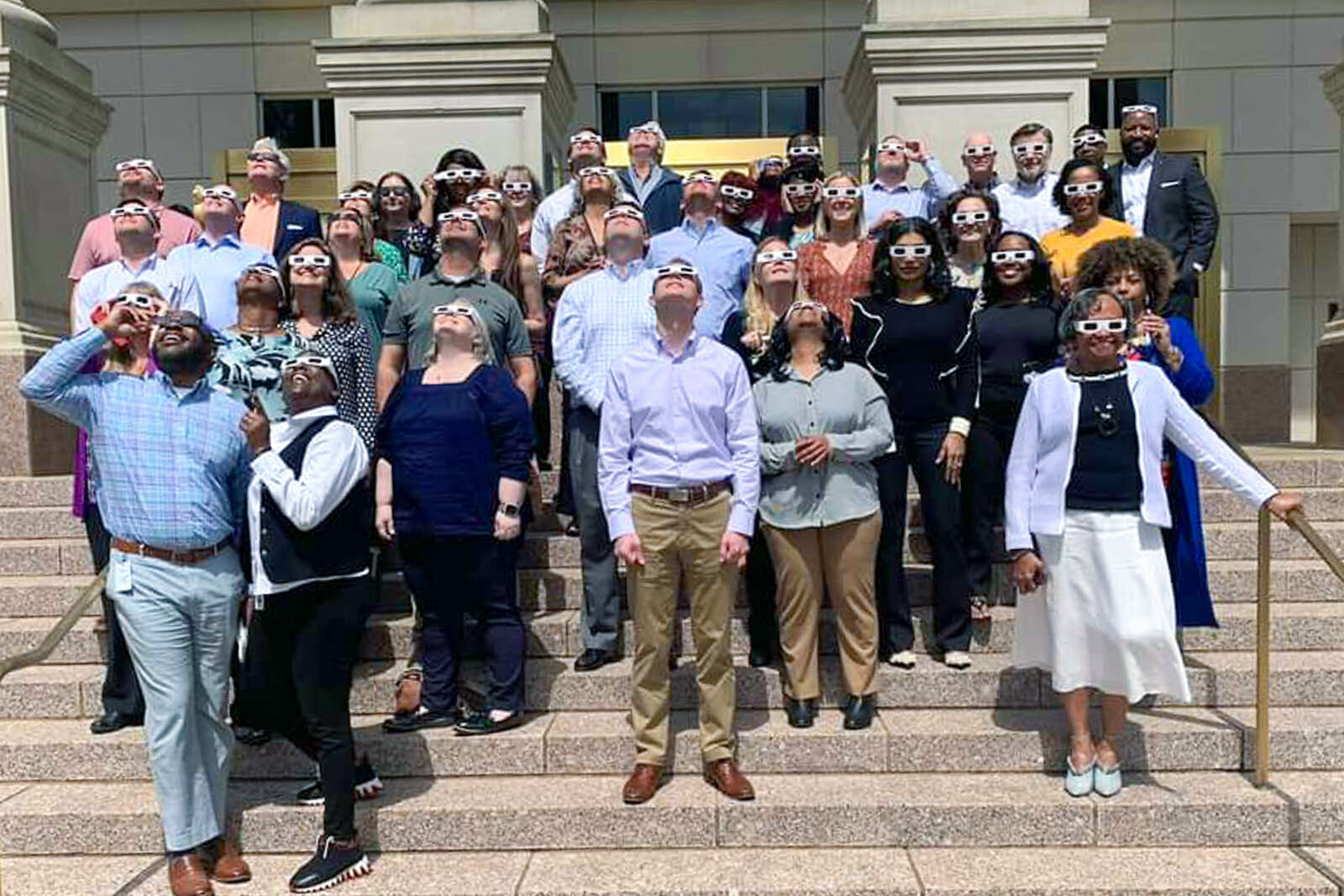 Group of Regions associates looking up to the sky with protective eyewear on to watch the solar eclipse.