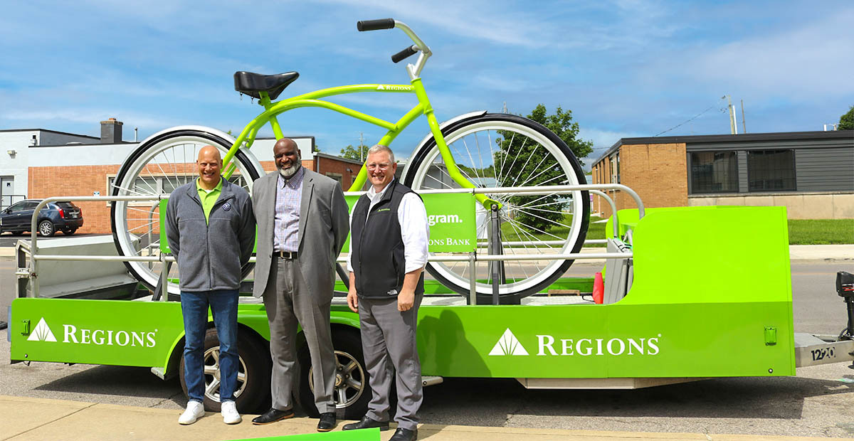 Bill Harris, Regions Commercial Banking relationship manager, Darius Adamson, superintendent of United Schools of Indianapolis (USI) and Erik Miner, Regions Greater Indy market executive standing in front of Regions Big Bike.