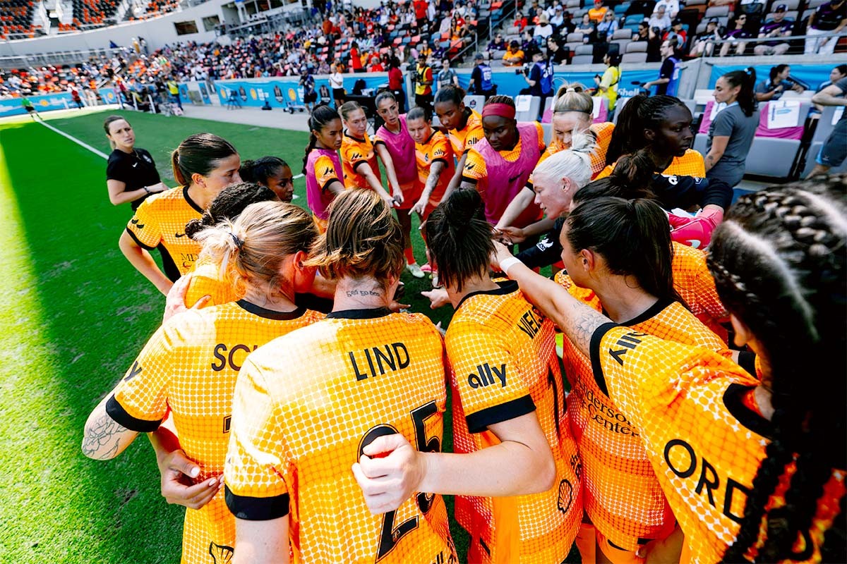 Team members of the Houston Dash huddle together during a game.