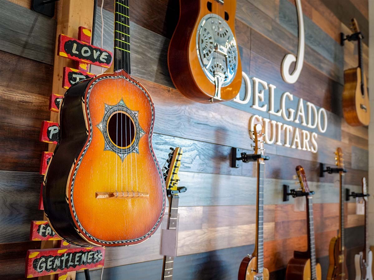 Delgato Guitars interior storefront sign surrounded by various types of guitars.