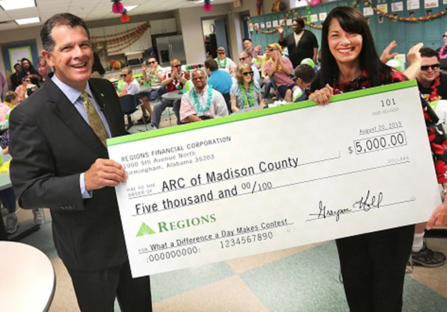 man and woman holding large Regions Bank check