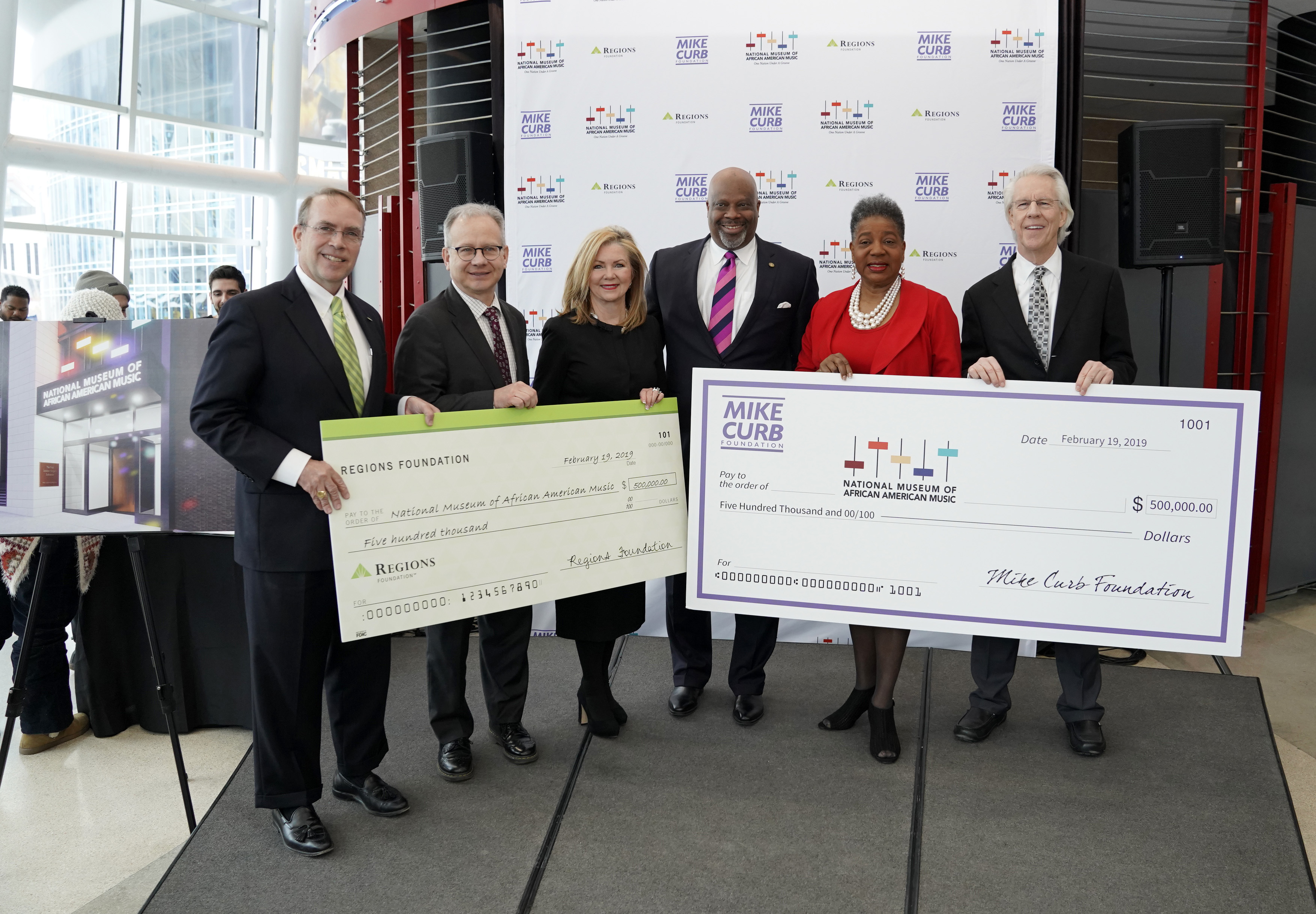 business people holding two large checks