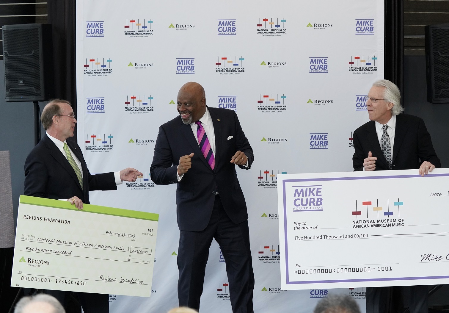 businessmen standing and holding large checks