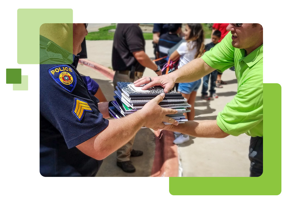 volunteer handing notebooks to police officer